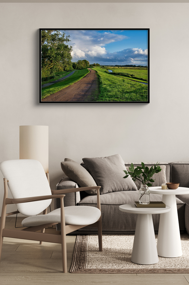 Acrylglasdruck mit grüner Landschaft im schwarzen Rahmen an der Wand über einem Sofa, neben einem hellen Sessel