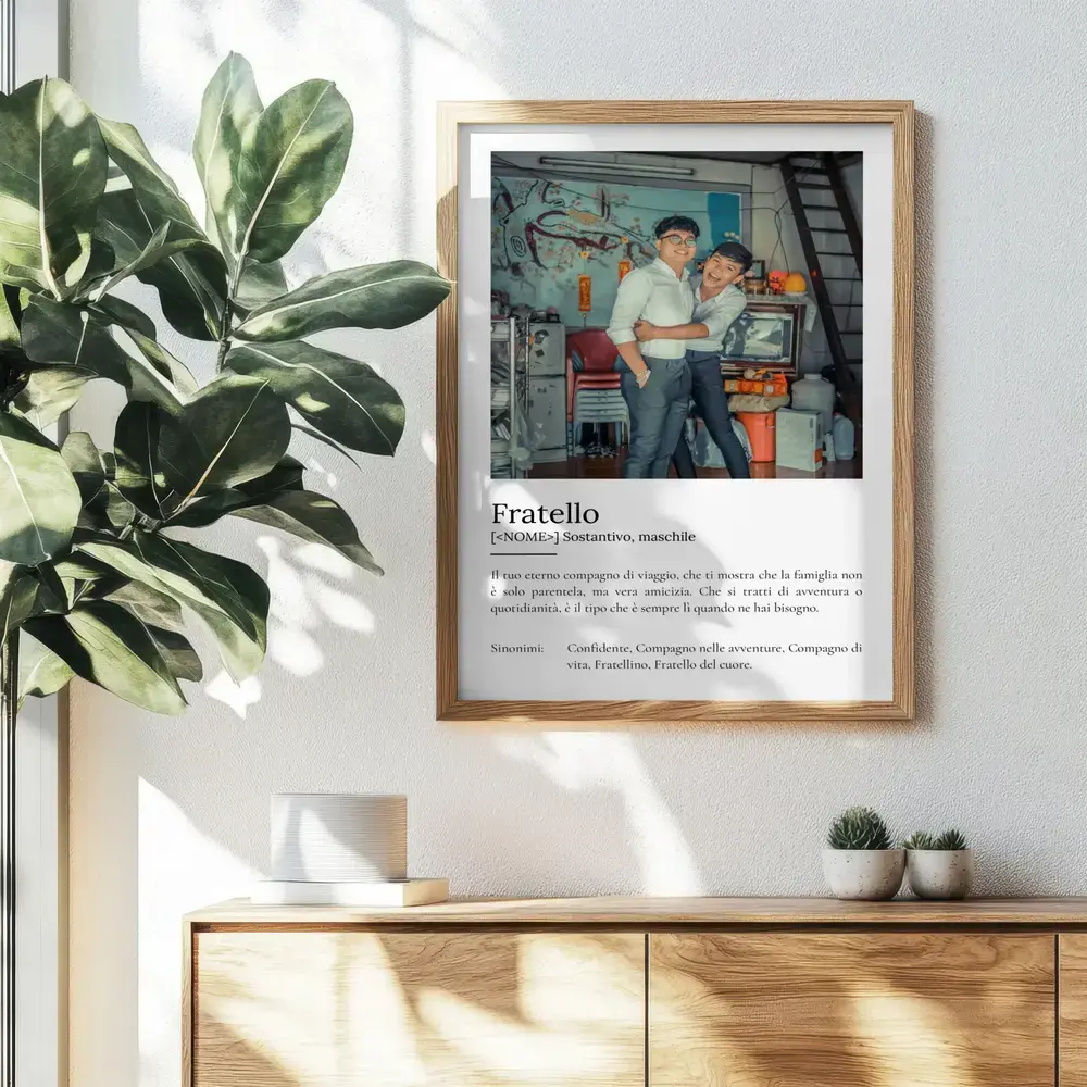 Poster con foto di due fratelli e definizione, in cornice di legno sopra una credenza accanto a una pianta