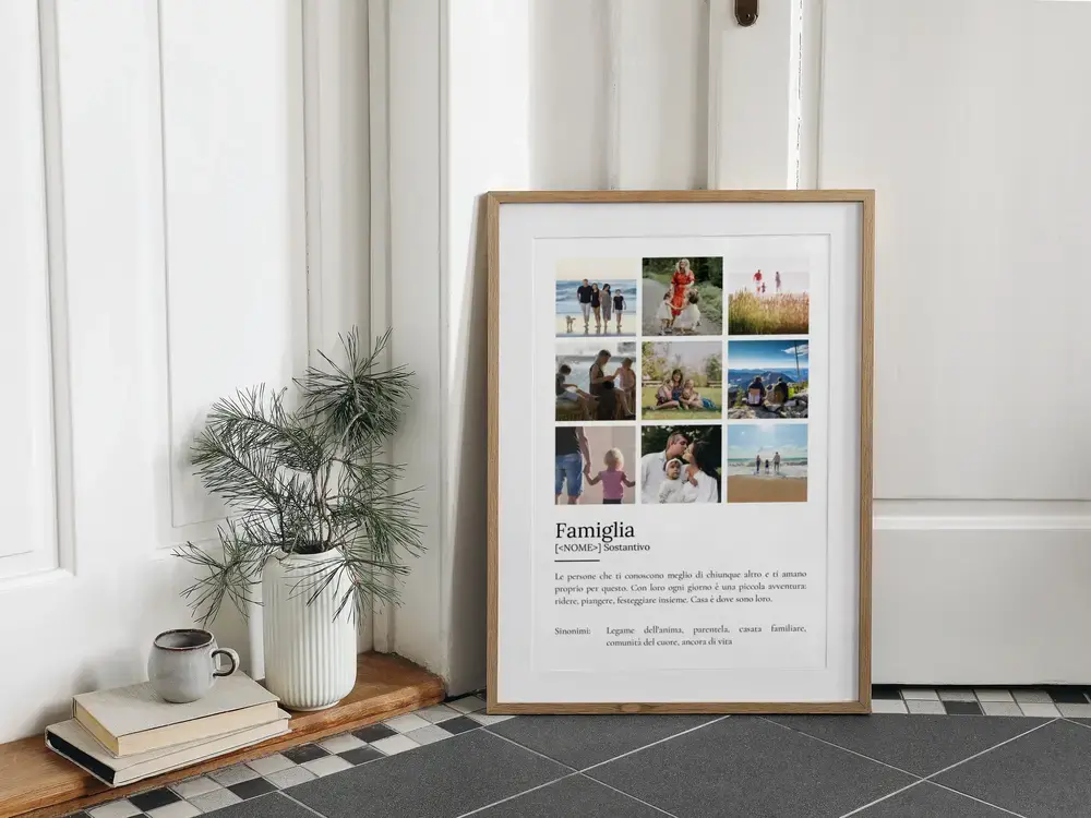 Poster con nove foto e definizione di famiglia, in cornice di legno appoggiata a terra accanto a libri e una pianta