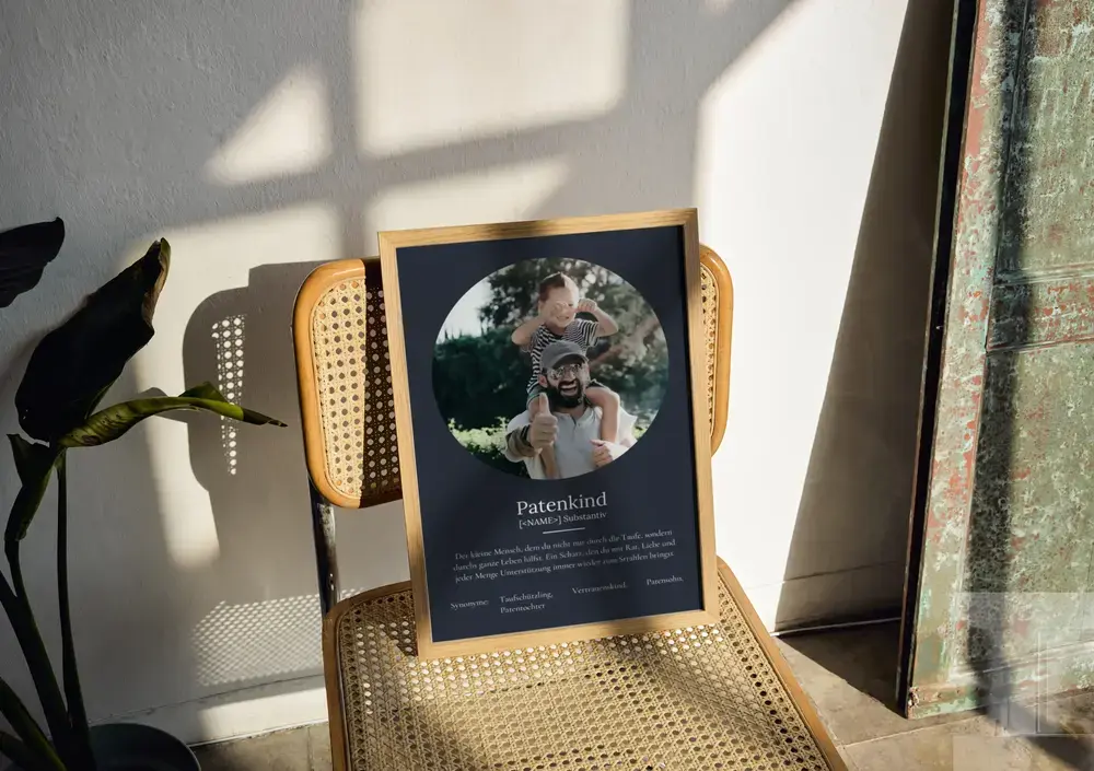 Definitionsposter fürs Patenkind mit rundem Foto auf Dunkelblau, im Naturholzrahmen auf einem Geflechtstuhl
