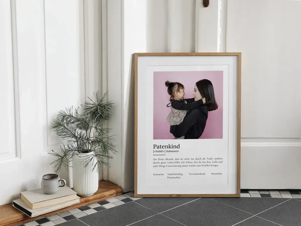 Fotoposter im Wörterbuch-Stil fürs Patenkind, im Naturholzrahmen am Boden neben einer Vase und Büchern