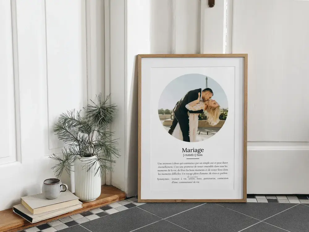 Affiche définition du mariage avec photo ronde de mariés, encadrée en bois et posée au sol près d’une plante