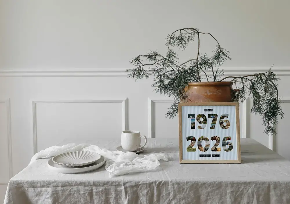 Pêle-mêle photo en forme de deux années, sur fond rayé bleu clair, encadré et posé sur une table dressée