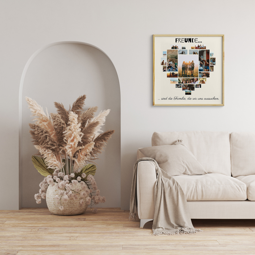 Herzförmige Fotocollage im hellen Holzrahmen über einem beigen Sofa neben einer Nische mit Trockenblumen