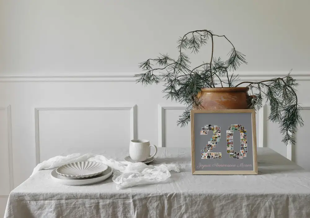 Collage photo 20 ans encadré en bois, posé sur une table nappée près de la vaisselle et d’une plante