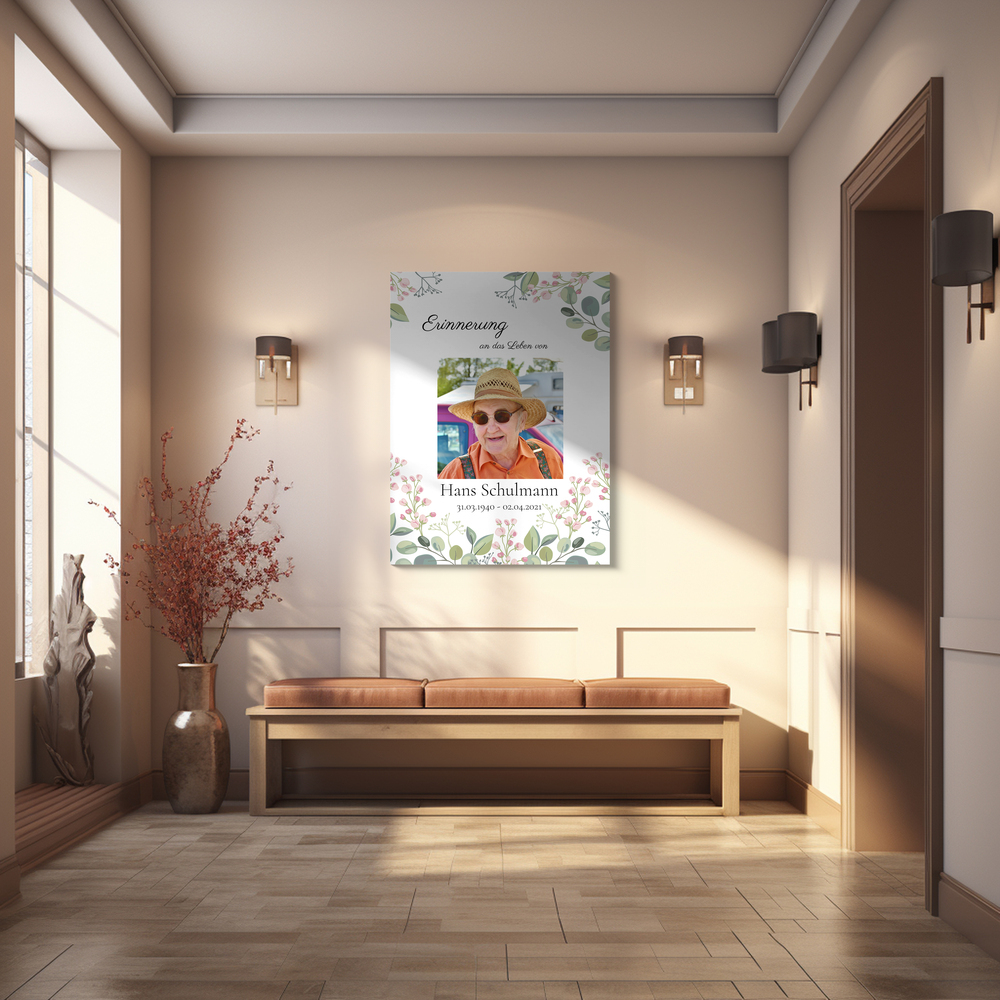 Trauerfoto mit floralem Rand und persönlichen Gedenkdaten an der Wand über einer Sitzbank im hellen Flur
