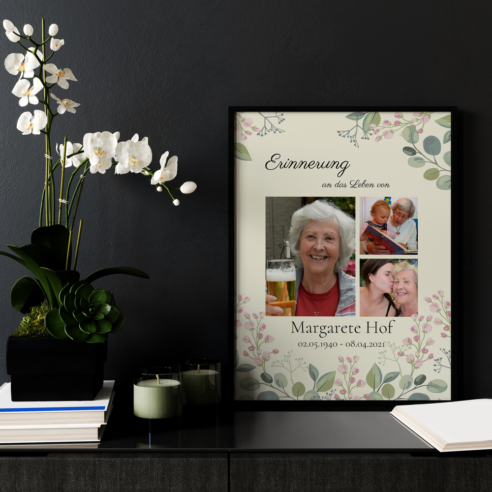 Trauercollage mit drei Fotos und Blumen im schwarzen Rahmen auf einer Kommode neben Orchideen und Kerzen